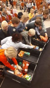 Kinderen van basisschool "de Bron" leggen producten in de kratten van de voedselbank